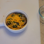 A warm keto breakfast bowl filled with browned sausage, fluffy scrambled eggs, sautéed onions and peppers, and melted cheese, arranged in a rustic ceramic bowl on a wooden surface.