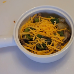 A warm keto breakfast bowl filled with browned sausage, fluffy scrambled eggs, sautéed onions and peppers, and melted cheese, arranged in a rustic ceramic bowl on a wooden surface.