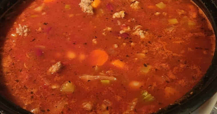 Bowl of pasta fagioli soup with kidney beans, ditalini pasta, carrots, ground turkey, spinach, and herbs in a tomato broth.